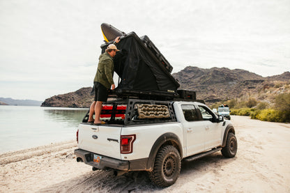 Loading a kayak beside a Ford Raptor with the ROAM Desperado on the rack