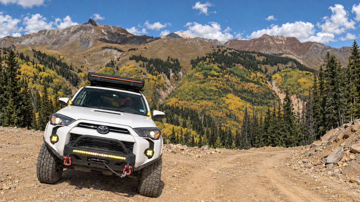 White Toyota 4Runner with a closed rooftop tent on a mountain trail among golden autumn aspens